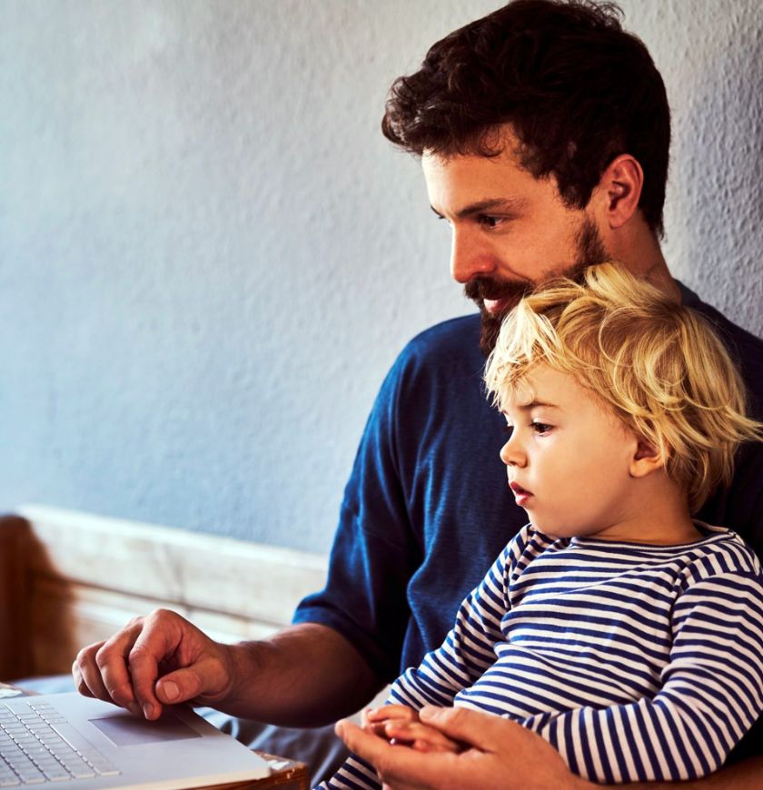Man with child reviewing benefits at home on laptop computer